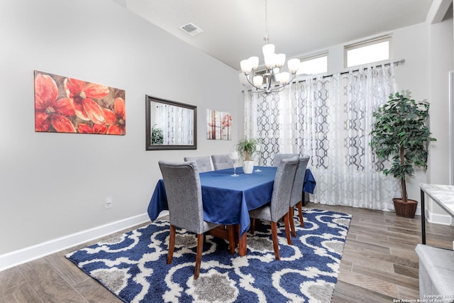 dining area with wood-type flooring and an inviting chandelier