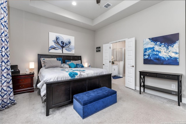 carpeted bedroom with ceiling fan, a raised ceiling, and ensuite bath