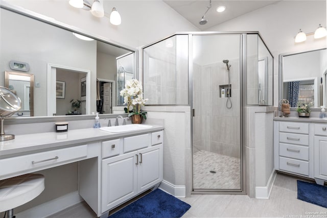 bathroom with a shower with shower door, vanity, and lofted ceiling