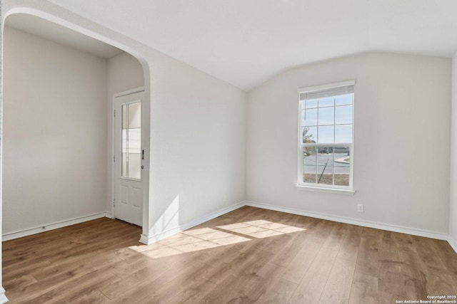 unfurnished room with light hardwood / wood-style floors and vaulted ceiling