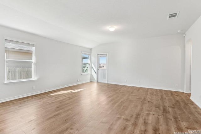 spare room with vaulted ceiling and light hardwood / wood-style floors