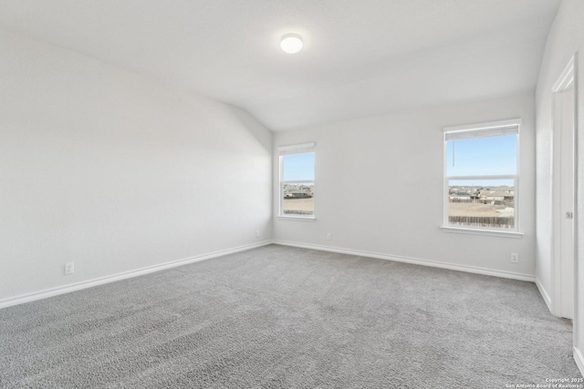 carpeted empty room featuring lofted ceiling