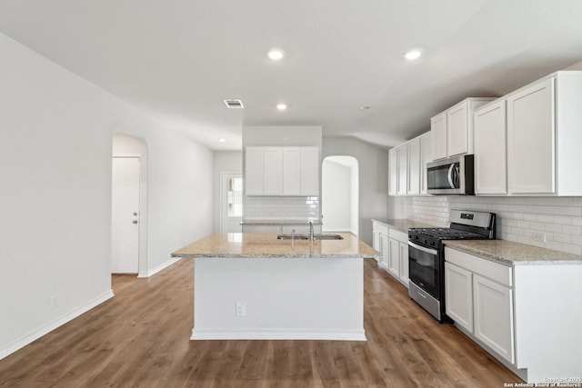 kitchen featuring white cabinets, stainless steel appliances, sink, and an island with sink