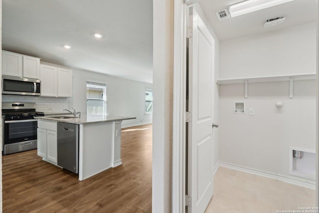 kitchen featuring sink, white cabinets, backsplash, light stone counters, and stainless steel appliances