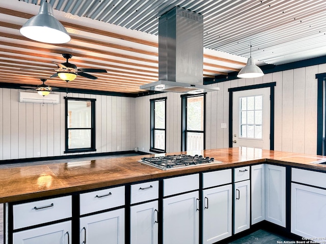 kitchen with wood counters, decorative light fixtures, island range hood, and wooden walls