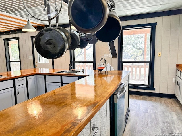 kitchen featuring sink, wooden counters, light wood-type flooring, and wood walls