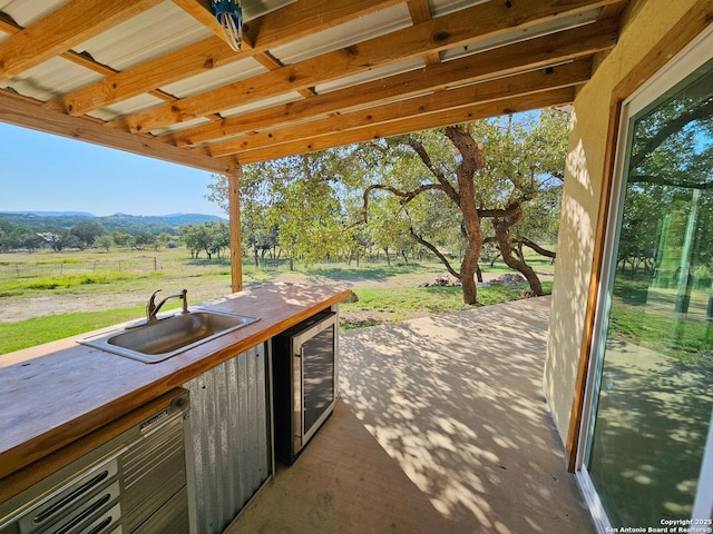 view of patio / terrace with wine cooler, sink, a rural view, and exterior kitchen