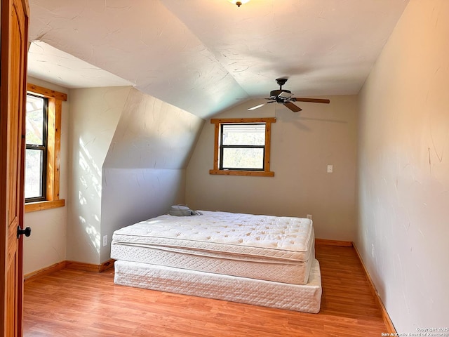 bedroom featuring ceiling fan, lofted ceiling, light hardwood / wood-style floors, and multiple windows