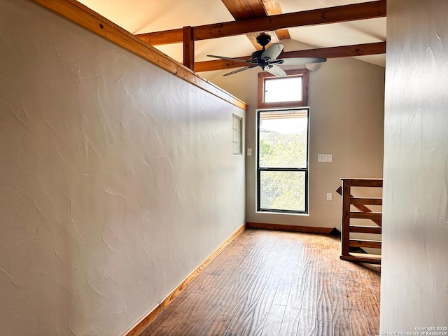 unfurnished room featuring ceiling fan, plenty of natural light, lofted ceiling with beams, and light wood-type flooring