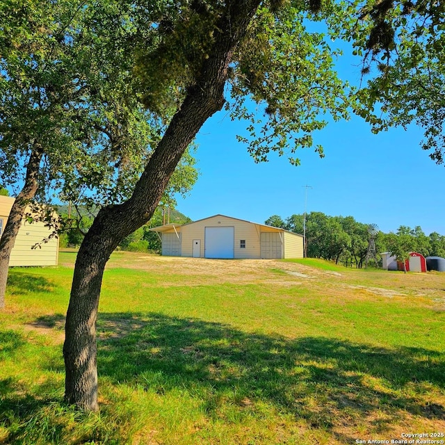 view of yard with a garage and an outbuilding