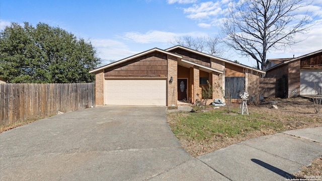 mid-century inspired home with a garage, fence, concrete driveway, and brick siding