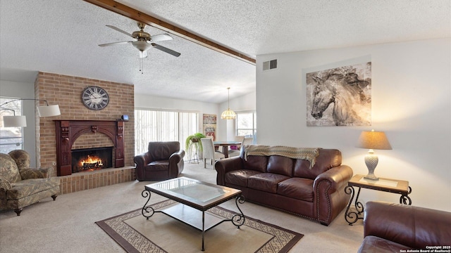 living room with a textured ceiling, vaulted ceiling with beams, ceiling fan, a brick fireplace, and light colored carpet