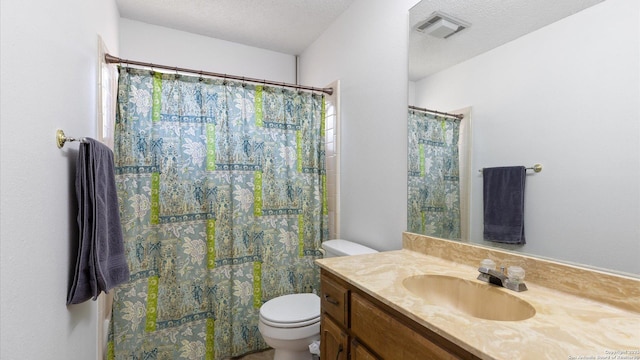 bathroom featuring visible vents, vanity, toilet, and a textured ceiling