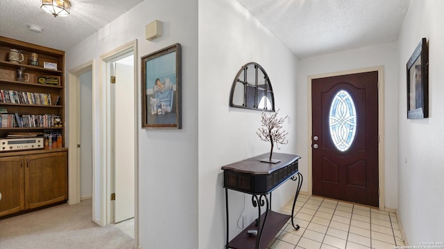 foyer with light tile patterned floors, a textured ceiling, and light colored carpet