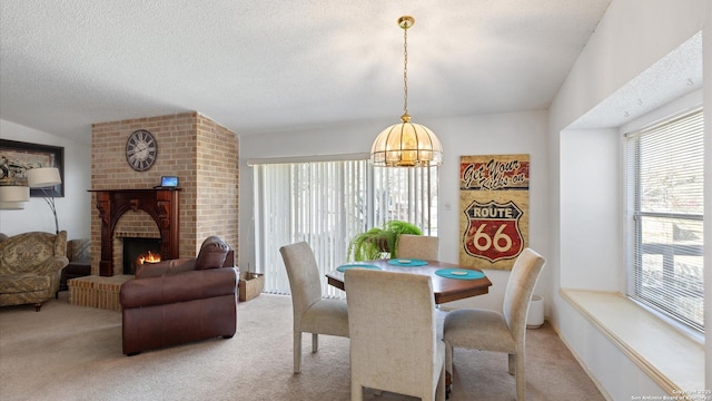 dining space with a textured ceiling, a fireplace, an inviting chandelier, and light colored carpet