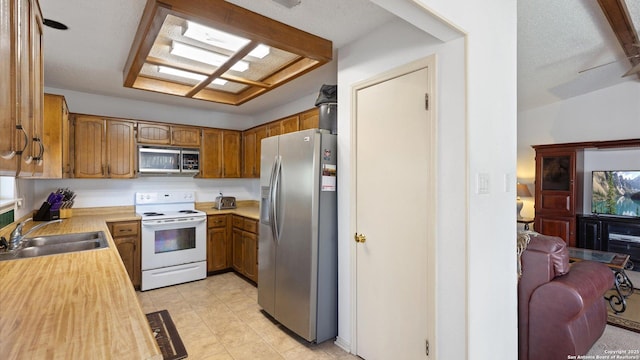 kitchen with appliances with stainless steel finishes, brown cabinets, light countertops, and a sink