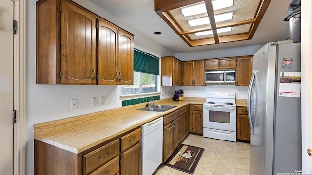 kitchen with stainless steel appliances, brown cabinetry, light countertops, and a sink