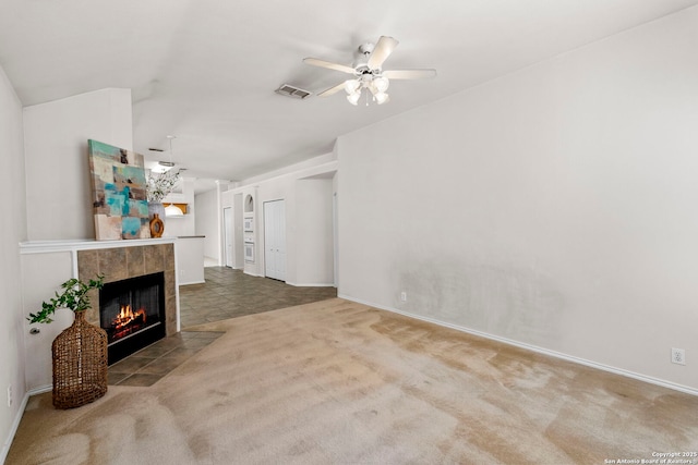 living room with ceiling fan, carpet flooring, and a tiled fireplace