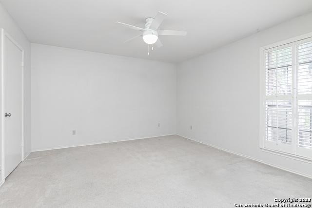 empty room with ceiling fan and light carpet