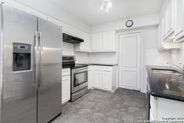 kitchen featuring appliances with stainless steel finishes, sink, backsplash, white cabinetry, and dark stone counters