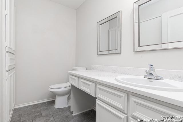 bathroom with toilet, vanity, and tile patterned flooring