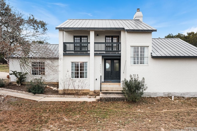 modern inspired farmhouse with french doors, a balcony, and a front yard