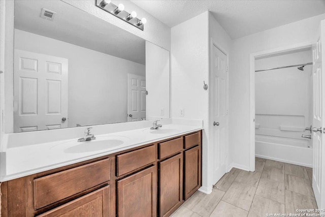 bathroom with washtub / shower combination, a textured ceiling, and vanity