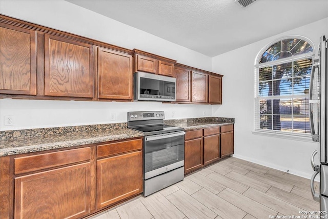 kitchen with appliances with stainless steel finishes and dark stone countertops