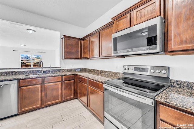 kitchen featuring sink, stainless steel appliances, and dark stone countertops