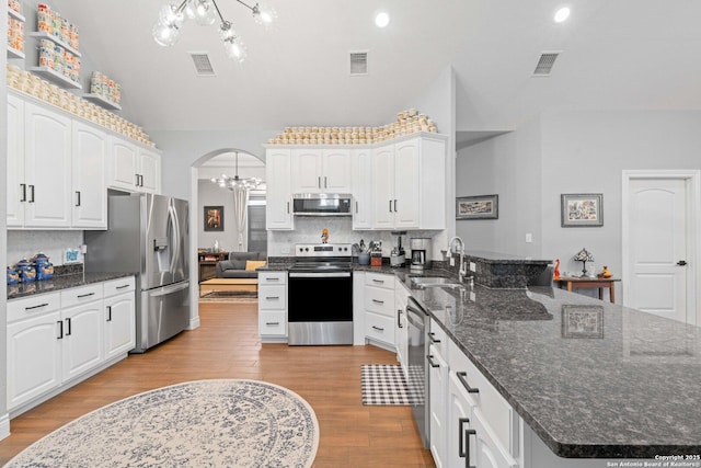 kitchen featuring sink, stainless steel appliances, white cabinetry, and hanging light fixtures