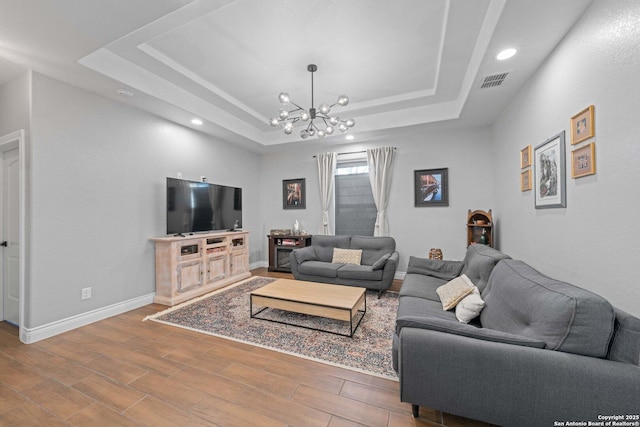 living room with an inviting chandelier and a tray ceiling