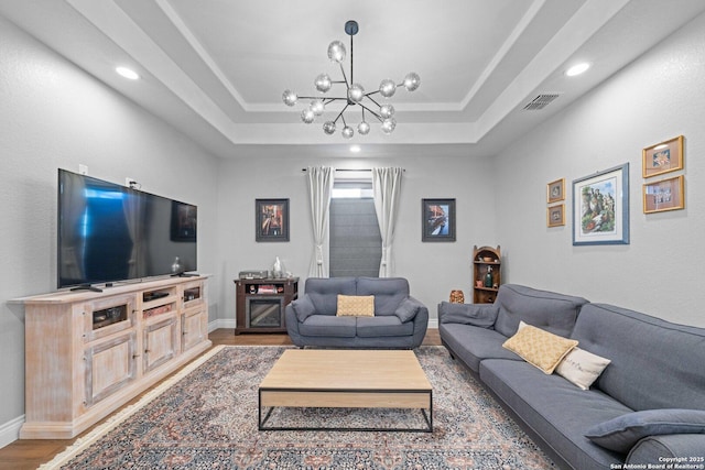 living room with a raised ceiling, hardwood / wood-style floors, and an inviting chandelier