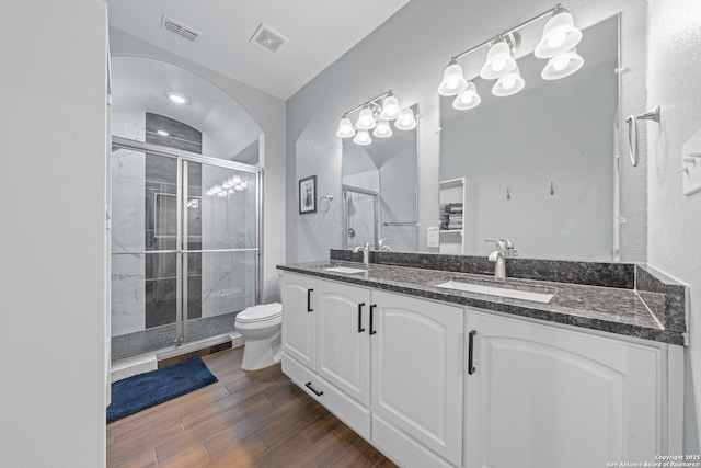 bathroom with vanity, toilet, and a shower with door