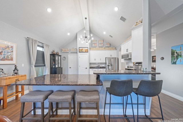 kitchen with white cabinetry, stainless steel appliances, decorative backsplash, dark hardwood / wood-style floors, and a breakfast bar