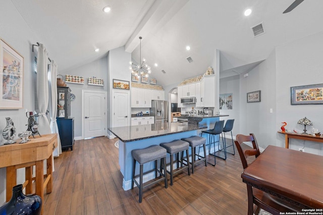 kitchen featuring appliances with stainless steel finishes, decorative light fixtures, white cabinetry, dark hardwood / wood-style flooring, and beam ceiling