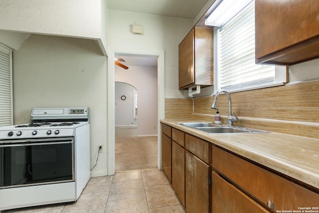 kitchen with sink, white range with gas stovetop, and light tile patterned flooring