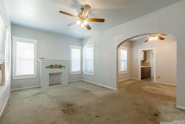 unfurnished living room featuring light colored carpet and ceiling fan