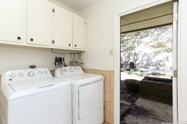 clothes washing area with cabinets and washer and dryer