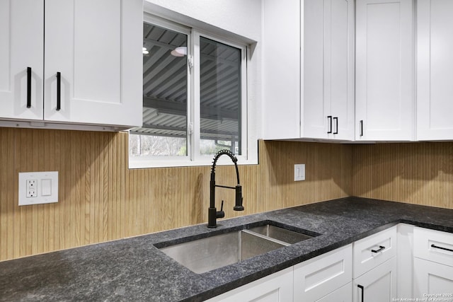 kitchen featuring sink, white cabinetry, and dark stone counters