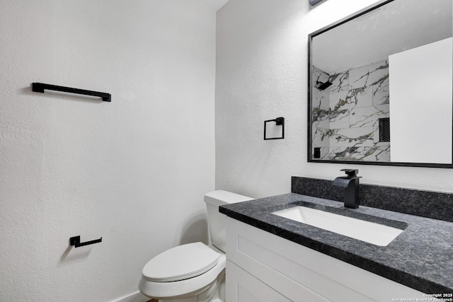 bathroom featuring vanity, toilet, and tiled shower