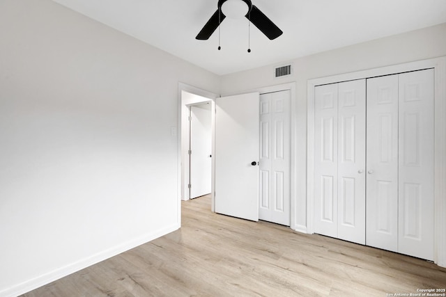 unfurnished bedroom featuring multiple closets, light wood-type flooring, and ceiling fan