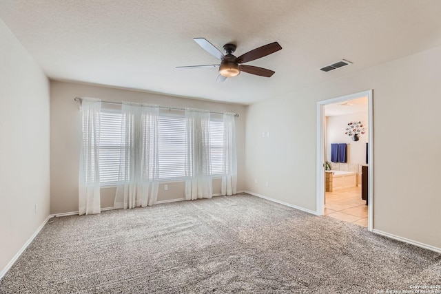 empty room with light carpet, ceiling fan, and a textured ceiling