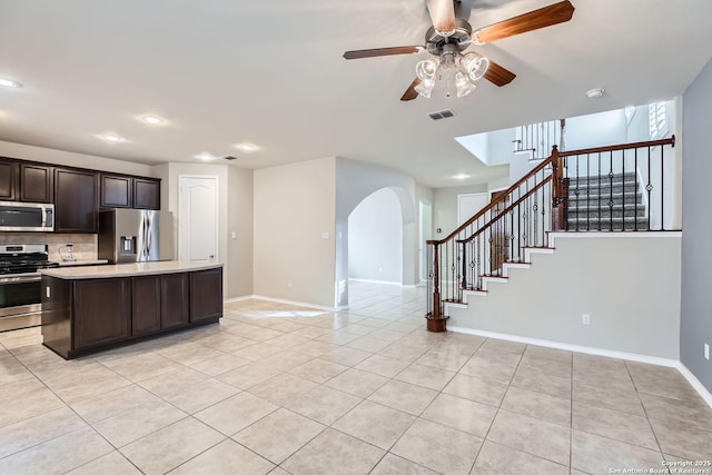 kitchen with tasteful backsplash, light tile patterned floors, dark brown cabinets, and appliances with stainless steel finishes