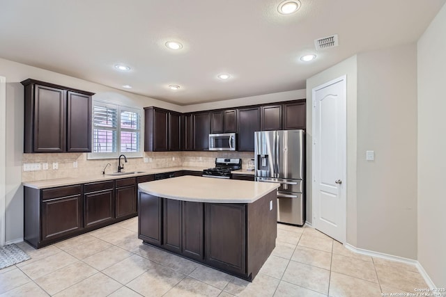 kitchen featuring sink, light tile patterned floors, appliances with stainless steel finishes, a center island, and dark brown cabinetry