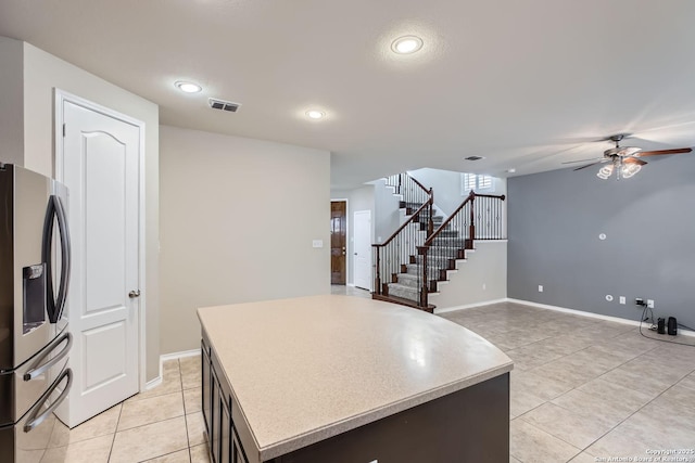 kitchen with light tile patterned floors, ceiling fan, dark brown cabinets, a center island, and stainless steel refrigerator with ice dispenser