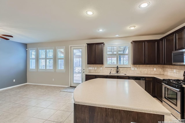 kitchen featuring sink, decorative backsplash, stainless steel appliances, and a center island