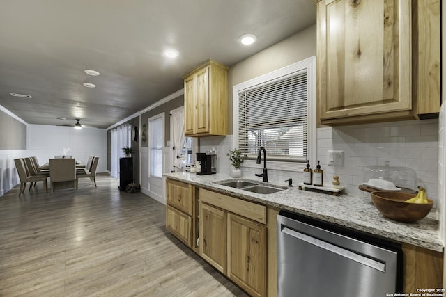 kitchen featuring crown molding, light stone countertops, stainless steel dishwasher, sink, and light wood-type flooring