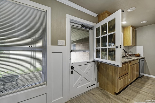 kitchen featuring dishwasher, sink, tasteful backsplash, ornamental molding, and light hardwood / wood-style floors