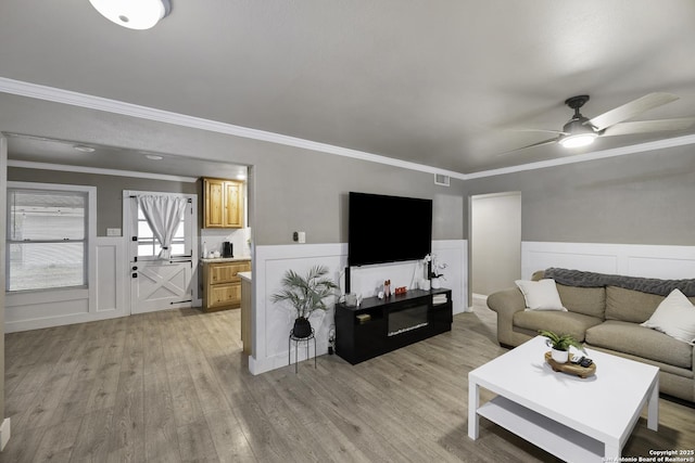 living room featuring crown molding, light hardwood / wood-style floors, and ceiling fan