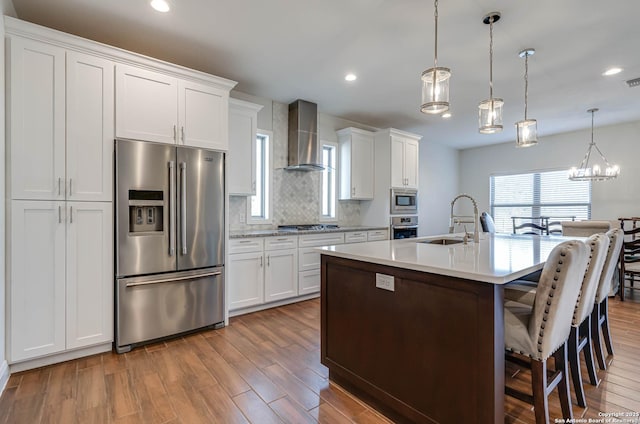 kitchen with sink, white cabinetry, wall chimney range hood, and stainless steel appliances